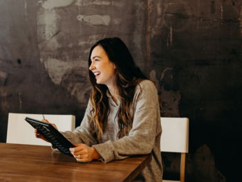 woman sitting around table holding tablet